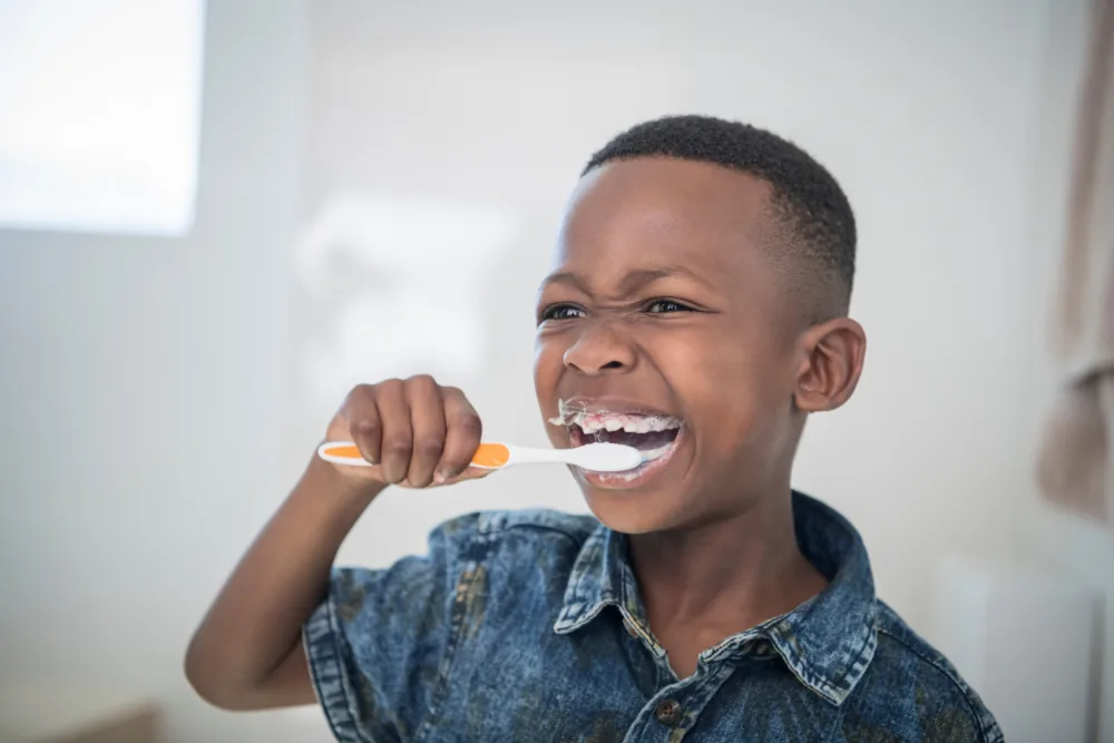 Young child brushing their teeth with fluoride toothpaste at home