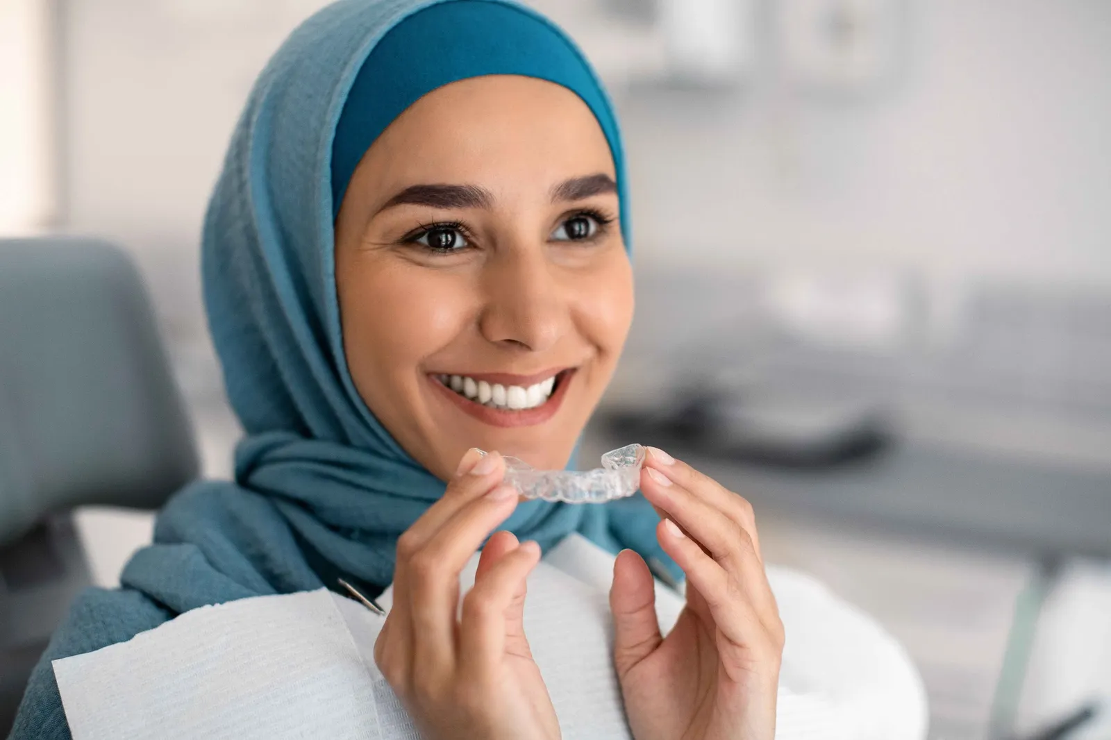 Patient holding a clear aligner for Invisalign teeth straightening treatment