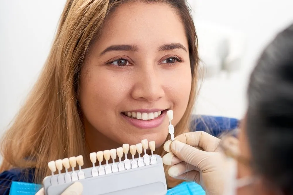 Dentist selecting veneer tooth shade with patient in Hornchurch